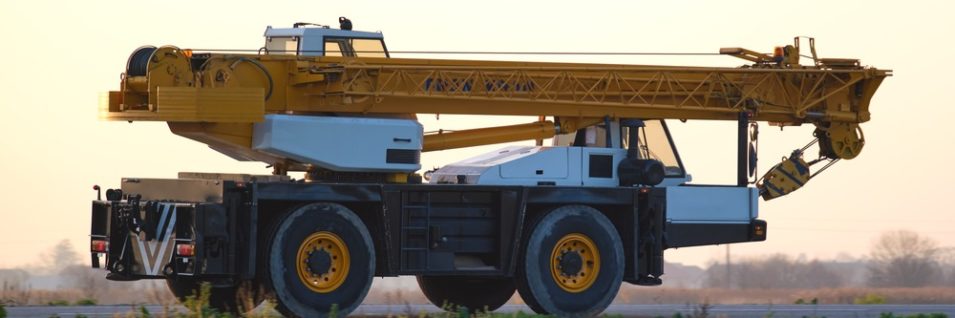 Heavy duty mobile lifting crane driving on intercity road at sunset. самоходный кран с маслом nerson