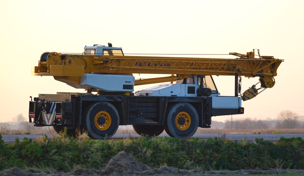 Heavy duty mobile lifting crane driving on intercity road at sunset. самоходный кран с маслом nerson